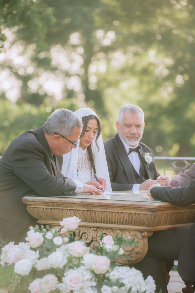 A bride signs documents at an outdoor Palestinian-Egyptian Muslim wedding at Park Château Estate.