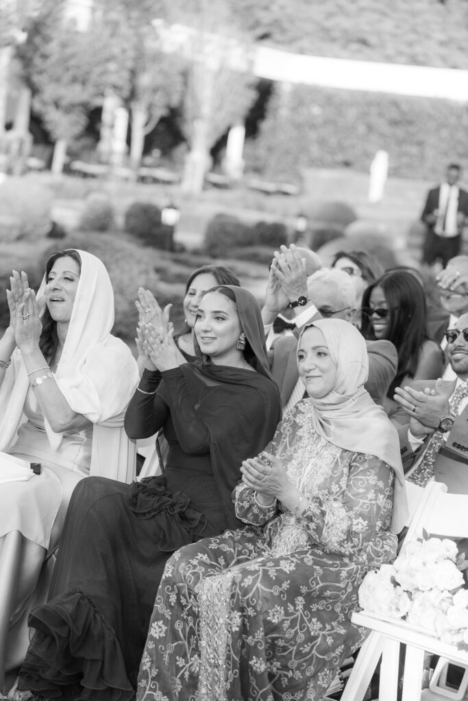 Guests wearing hijabs clap during a Palestinian-Egyptian Muslim wedding at Park Château Estate & Gardens.