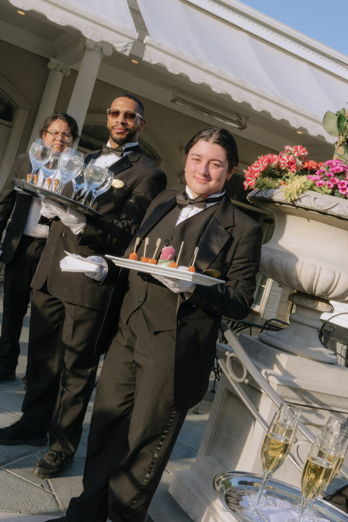 Three waiters in tuxedos hold trays of drinks and appetizers for a wedding at Park Chateau.
