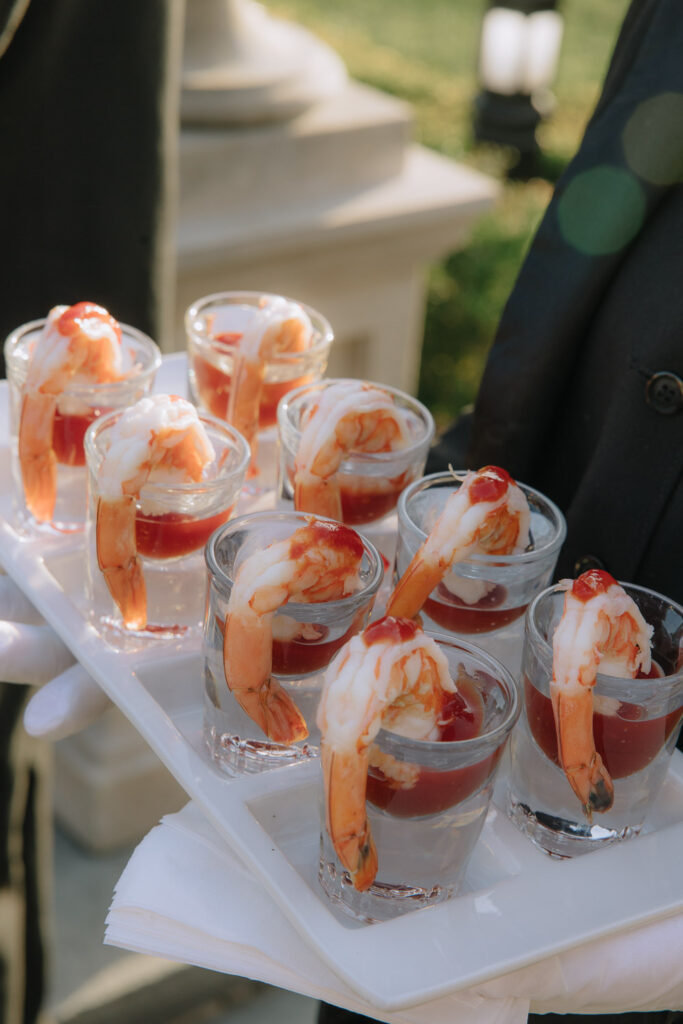 A caterer holding a tray of shrimp cocktail in shot glasses at a Park Chateau wedding.