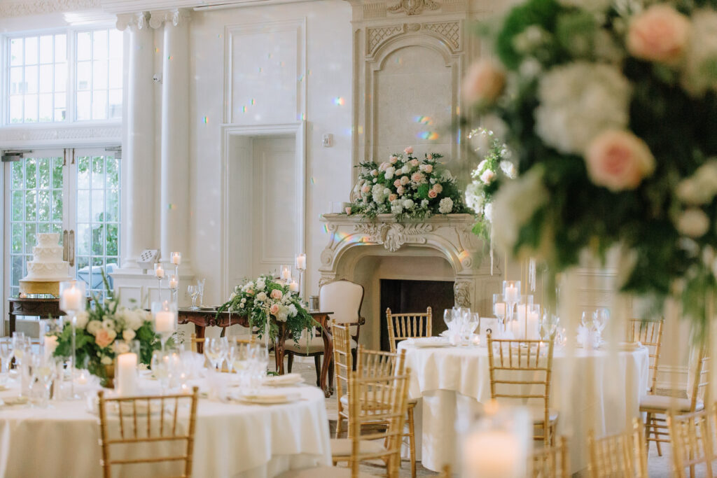 A formal wedding reception room with white draped tables, gold chairs, and floral arrangements at Park Chateau, New Brunswick.