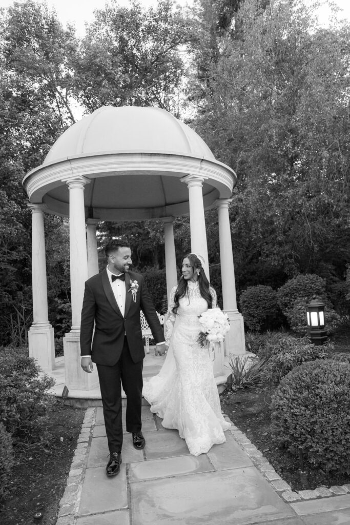 A newlywed couple walking hand-in-hand in the formal gardens at Park Chateau, New Brunswick, New Jersey.