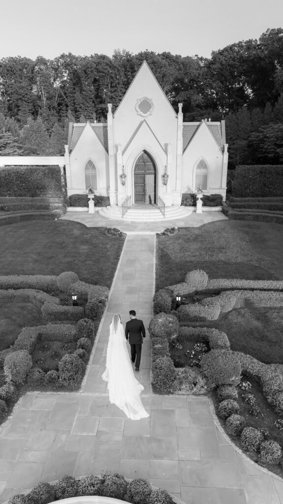 A newlywed couple walks down a stone path in the formal gardens at Park Chateau in East Brunswick, New Jersey.