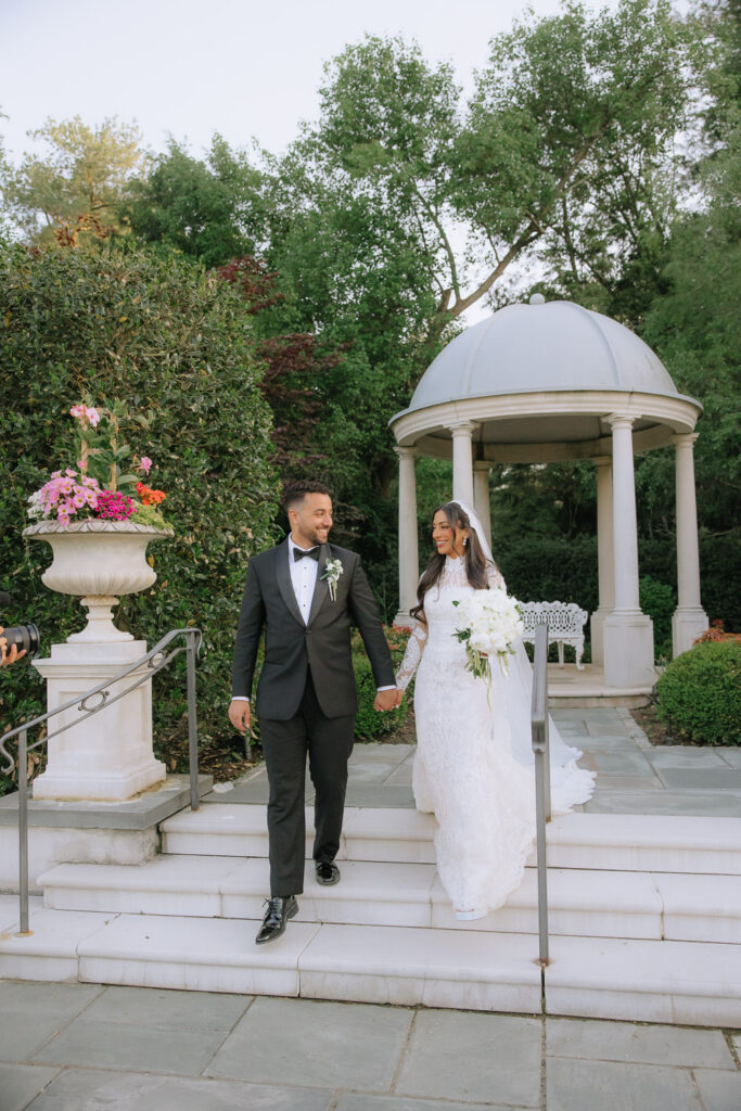 A newlywed couple walks hand in hand down stairs at Park Château Estate & Gardens.