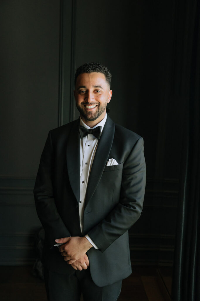 A man in a tuxedo smiles at the camera at a Palestinian-Egyptian Muslim wedding at Park Château Estate.