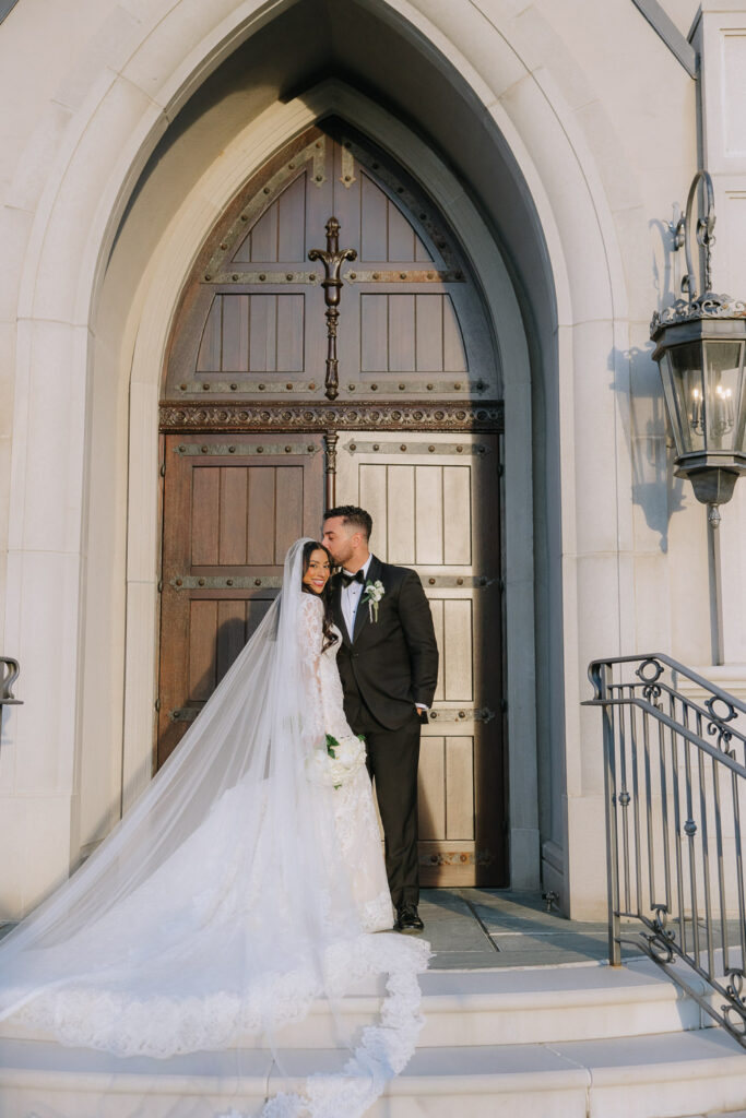 The groom kisses the bride's forehead on the steps of the Park Chateau in East Brunswick, New Jersey.