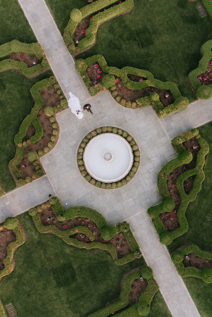 Aerial view of a couple walking on a paved pathway around a fountain at Park Chateau in New Brunswick, New Jersey.