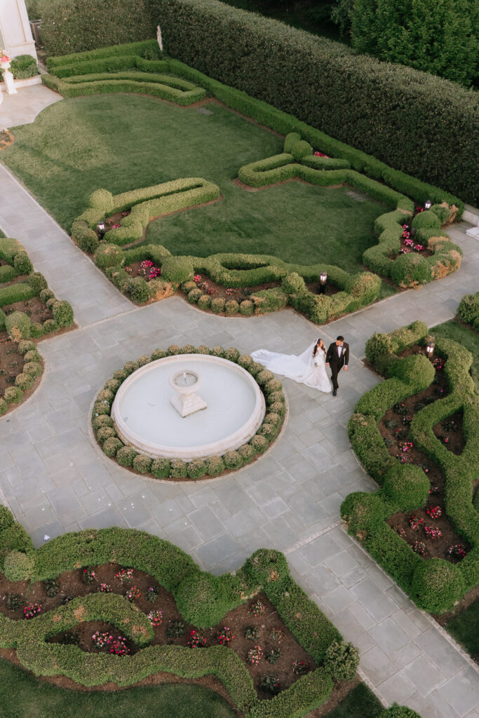 A drone shot shows the wedding couple walking hand-in-hand through the formal gardens at Park Chateau.