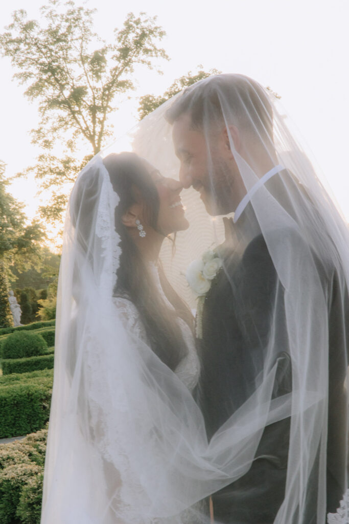 A bride and groom touch noses under a sheer veil at Park Chateau Estate & Gardens wedding.