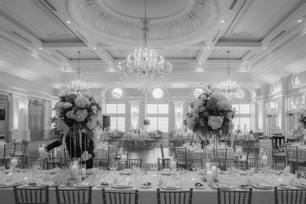 An elegant wedding reception room with chandeliers and floral centerpieces at Park Chateau in New Jersey.