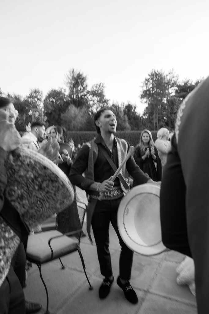 A musician holding a drum and drumsticks during a Zaffa procession at a Palestinian-Egyptian Muslim wedding.