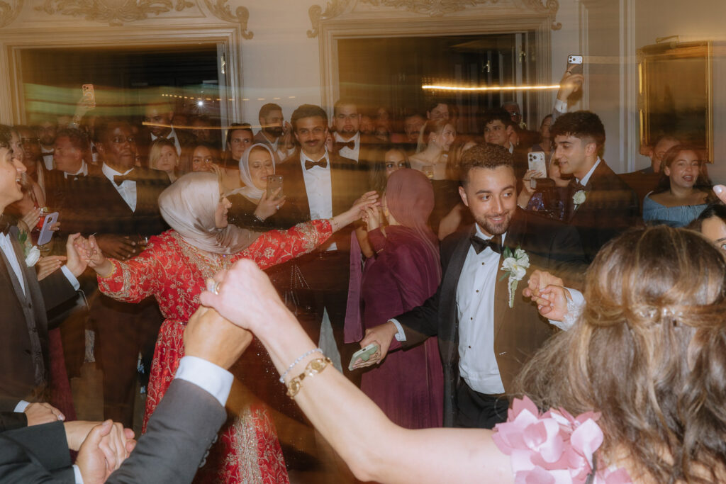 Wedding guests in cultural attire dance during a Zaffa procession at Park Château Estate & Gardens.