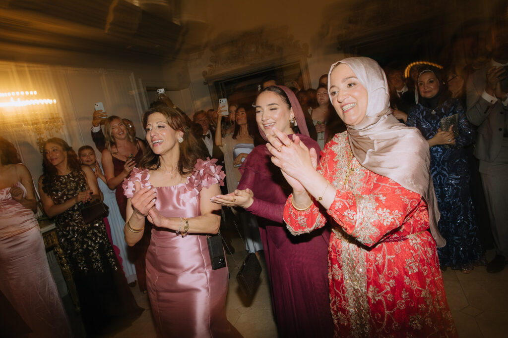 Wedding guests in cultural clothing clap and smile during a Palestinian-Egyptian wedding at Park Château.