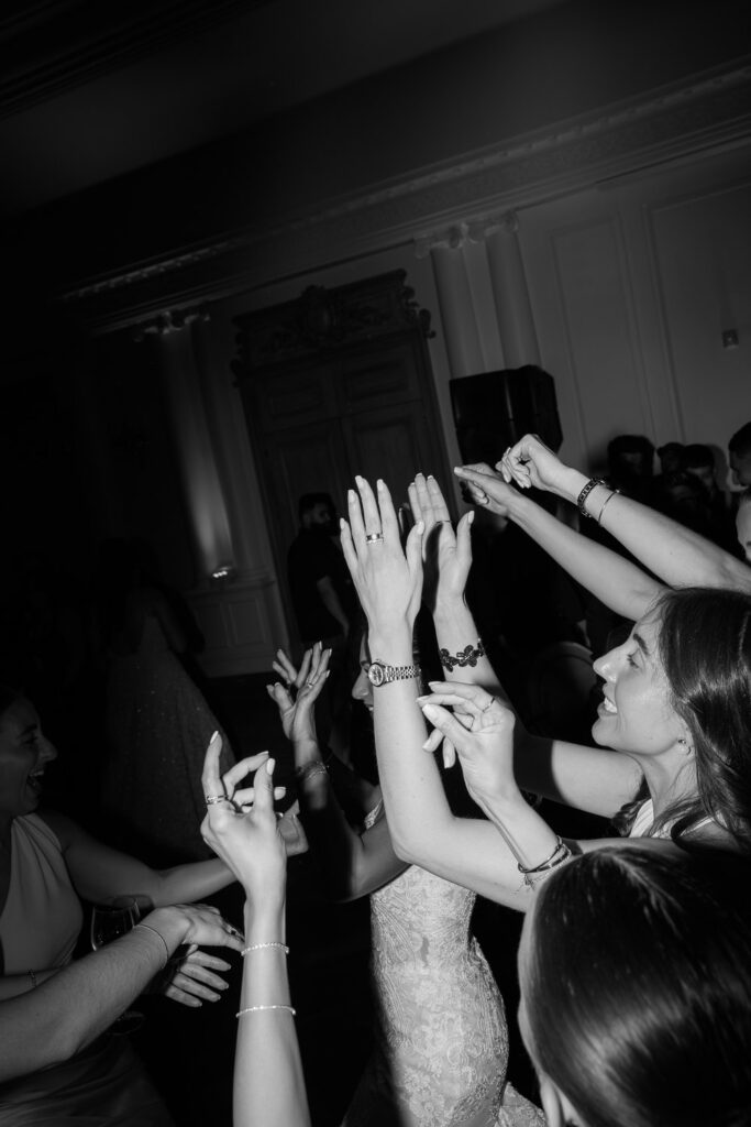 Wedding guests dance with hands raised high during a reception at Park Chateau Estate & Gardens.