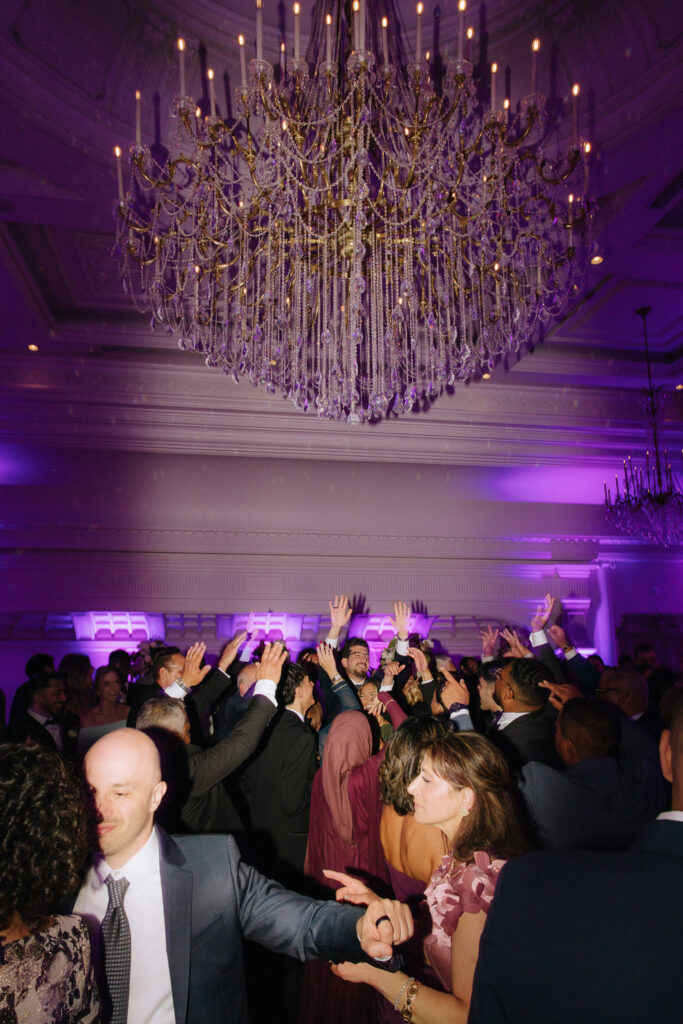 Guests dance under a crystal chandelier at a wedding reception at Park Chateau in New Brunswick, NJ.