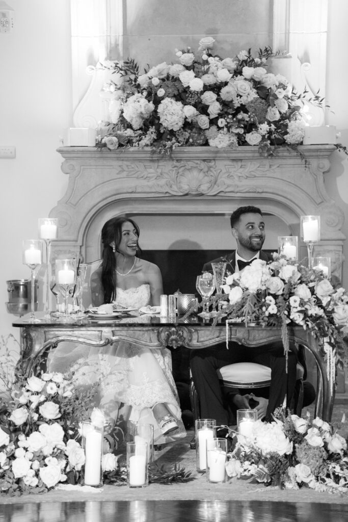 A bride and groom sit at their wedding reception head table at Park Chateau Estate & Gardens.
