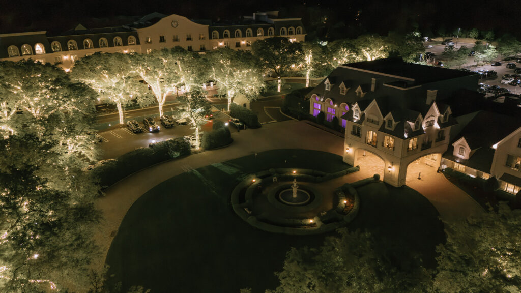 Aerial night view of Park Chateau Estate & Gardens, featuring lit-up trees and a fountain.