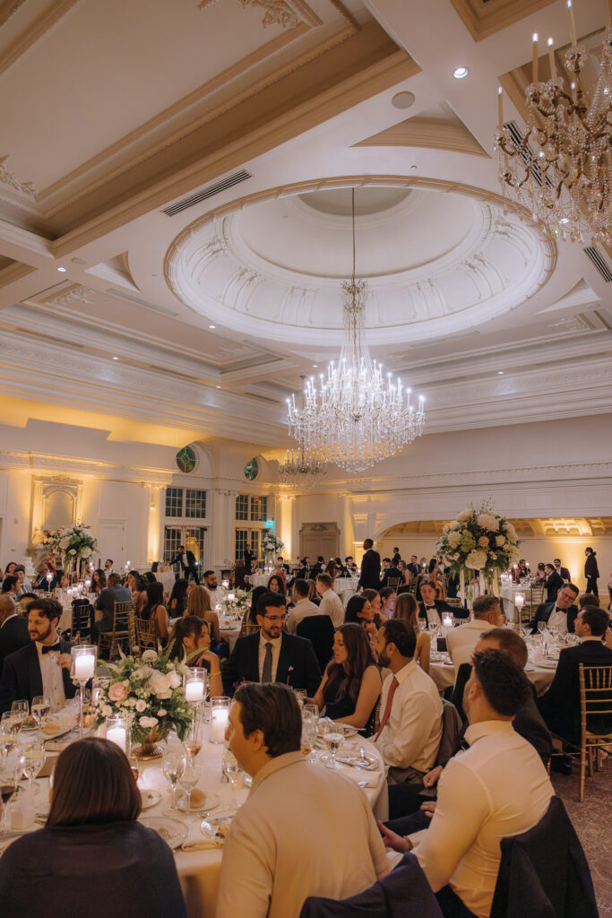 Guests seated at tables under grand chandeliers in the Park Chateau Estate & Gardens ballroom.