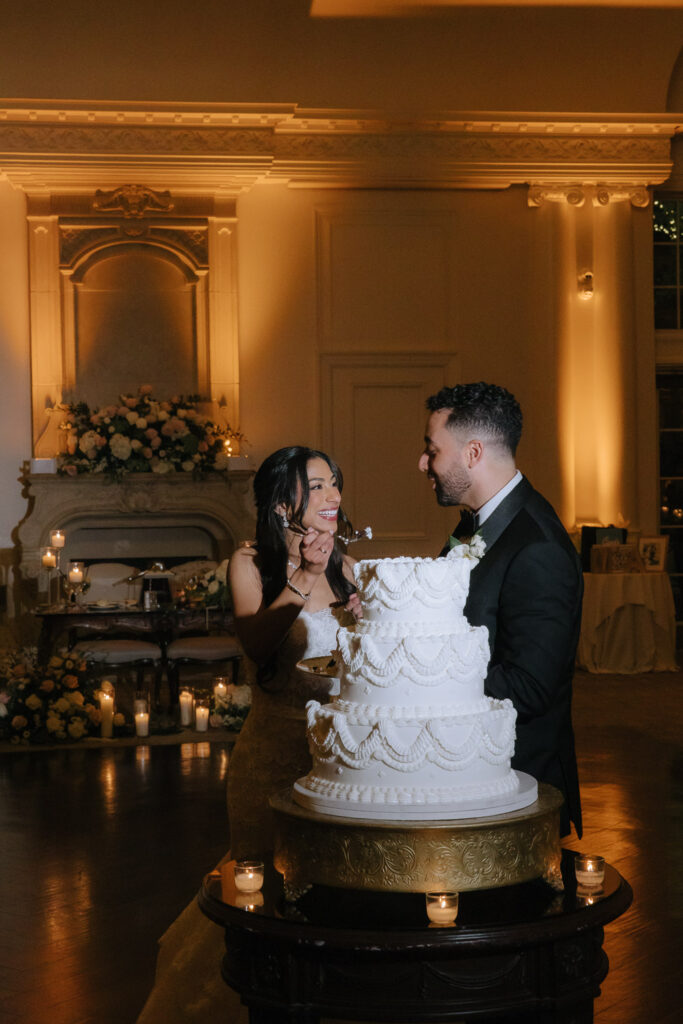 Menah and Ashraf cut their white wedding cake at Park Chateau Estate & Gardens in New Brunswick, NJ.