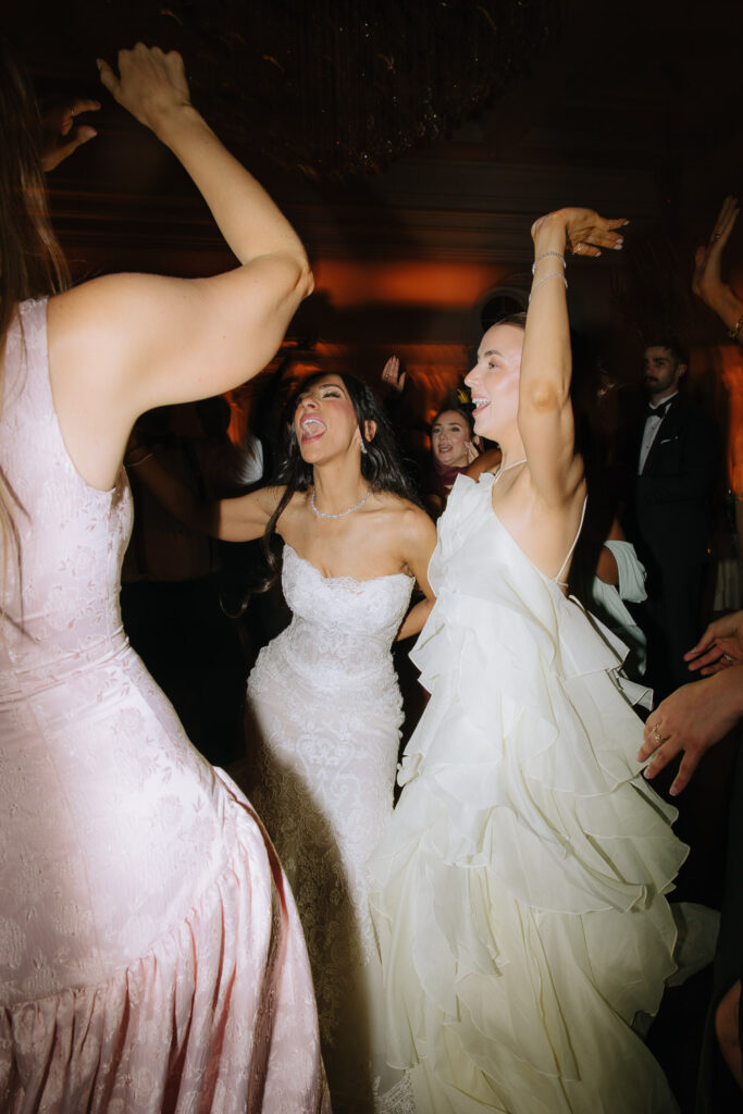 The bride and a guest dance with arms raised at the Palestinian-Egyptian Muslim wedding at Park Chateau.
