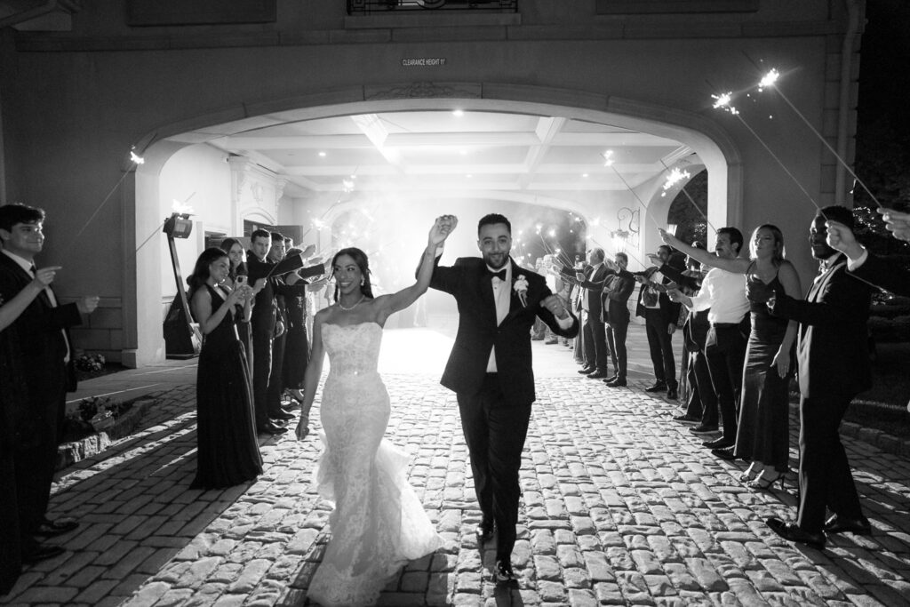 A newlywed couple exits Park Chateau Estate, walking through guests holding sparklers, a Palestinian-Egyptian wedding in New Jersey.